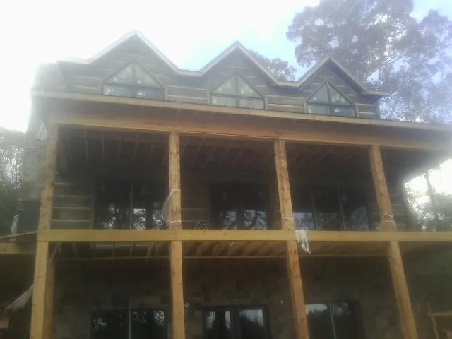 Dormers and porch framing on a large log home under construction — Roof Coating work by our crew in Lanexa