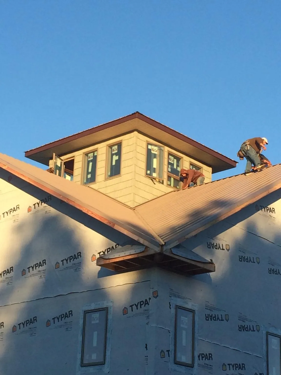 Roofers working around a rooftop cupola on a new metal roof at sunset — Roof Waterproofing in Lanexa by Roofing Brothers